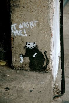 a black and white cat is painted on the side of a building with words that read i want it all