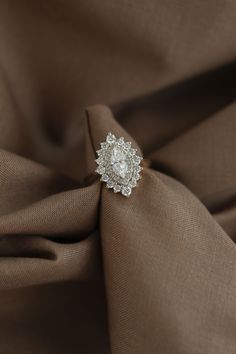 a diamond ring sitting on top of a brown cloth covered in satin material and fabric