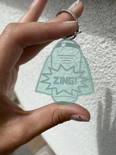 a person holding up a plastic keychain with the word zinc on it