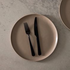 two black forks and spoons on a white plate next to each other in front of a marble counter top