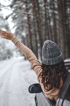 a woman is sitting in her car waving out the window