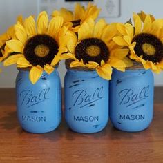 three blue mason jars with sunflowers in them