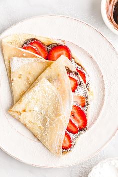 two desserts on a plate with strawberries and powdered sugar