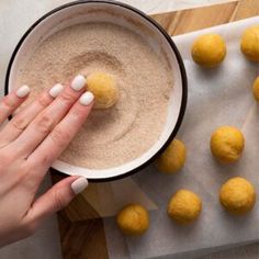 a person holding a doughnut in their hand near some balls of doughnuts