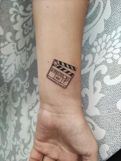 a woman's wrist with a movie clapper tattoo on it