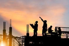 people standing on top of a building with the sun setting in the backround