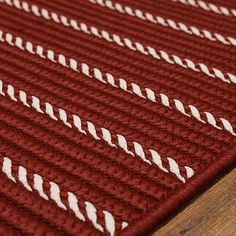 a red and white rug on top of a wooden floor next to a brown table