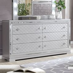 a large silver dresser sitting in a living room next to a white rug and potted plant