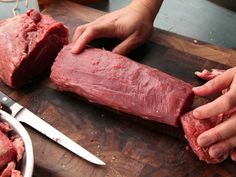 a person cutting up meat on top of a wooden table