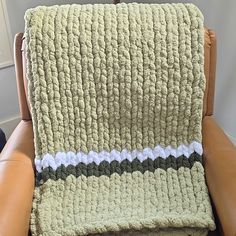 a crocheted blanket sitting on top of a leather chair