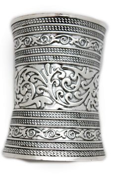 a silver bracelet with intricate designs on the outside and inside, sitting against a white background