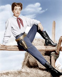 a woman sitting on top of a wooden bench wearing boots and a shirt with an attached tie