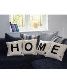 two pillows that say home on them in front of a blue couch with striped pillows