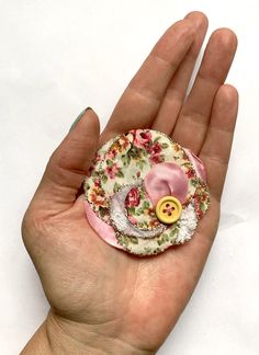 a hand holding a small button with flowers on it