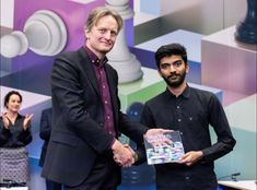 two men shaking hands while standing next to each other in front of a colorful background