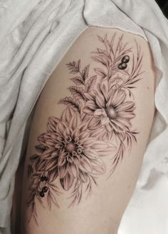 a woman's thigh with flowers and leaves on the side, in black and white