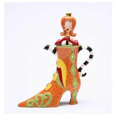 a ceramic figurine of a woman sitting on top of a boot