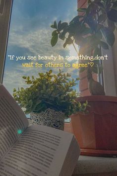 an open book sitting on top of a window sill next to a potted plant