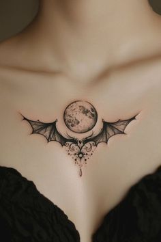 a woman's chest with a bat and moon tattoo on the top of it