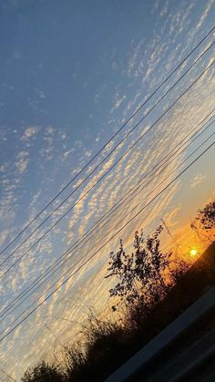 the sun is setting behind some power lines