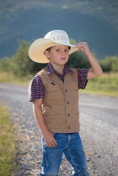 The Youth Bronco Canvas Vest is made from our premium 12 ounce cotton canvas, is durable and strong, just what the upcoming little working rancher and cowboys need. This vest has several unique elements, one being the shoulder western yoke on the front and back of the vest, an open v-neck with lapel and four Wyoming Traders logo buttons. This vest is lined with a polyester satin lining. The Bronco Vest has four front welt pockets, two for your hands and two chest pockets, all lined with a polyes Western Rodeo Vest, Western Style Sleeveless Vest For Rodeo, Athena Lee, Canvas Vest, Brown Vest, Cream Shirt, Tractor Supply, The Youth, Kids Outerwear