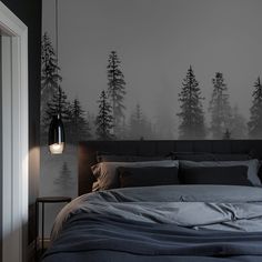 a large bed sitting under a window next to a wall with trees painted on it