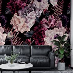 a living room with black leather couches and large floral wallpaper on the walls