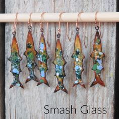 five glass fish hanging from hooks on a wooden board with the words smash glass written below them