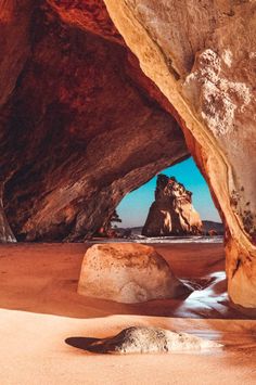 a rock formation in the middle of a sandy beach