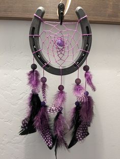 a purple and black dream catcher hanging on a wall