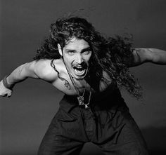 a man with long hair and piercings on his chest is posing for a black and white photo