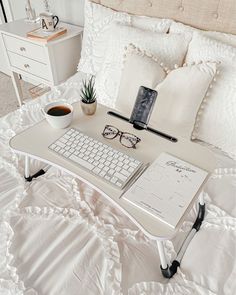 a laptop computer sitting on top of a white bed next to a cup of coffee