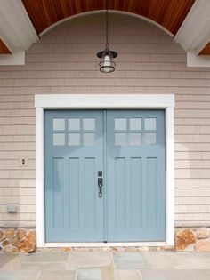 two blue doors are on the side of a house with white trim and wood ceiling