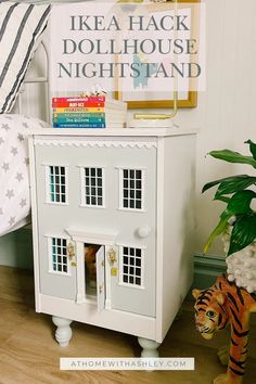 a doll house sitting on top of a wooden floor next to a bed and a potted plant