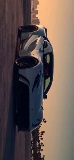 a blue sports car is parked on the side of the road next to some water