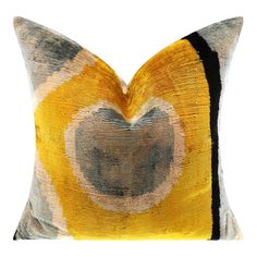 a yellow and black pillow with a heart shaped design on the front, sitting on a white background