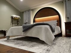 a large bed sitting on top of a wooden floor next to a white and gray rug