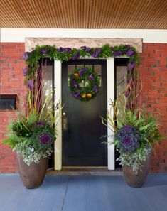 two large planters with wreaths on them are in front of a door