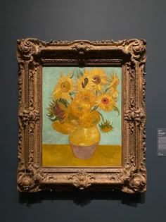 a painting on display in a museum with a vase full of sunflowers behind it