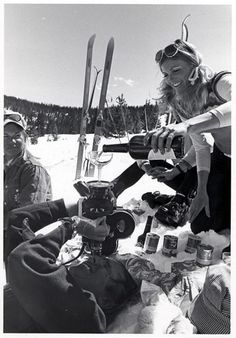 a group of people sitting on top of a snow covered ground next to skis