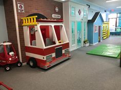 children's play area with firetruck and other toys in large room setting