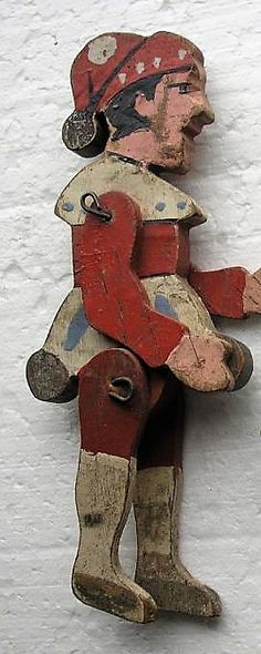 an old wooden toy is standing in the snow with its arms out and feet apart