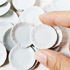 a hand is touching some white plates on the table