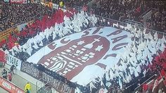 an aerial view of a large banner in the middle of a soccer field with fans standing around it