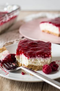 a piece of cheesecake on a plate with raspberry sauce and a fork