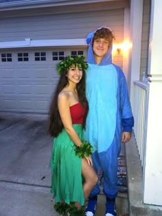 two people dressed up in costumes standing next to each other near a house with lights on