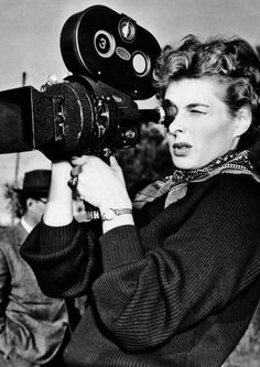 a woman holding a camera up to the side of her face with another person looking at it