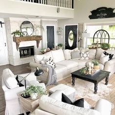 a living room filled with white furniture and lots of pillows on top of it's couches