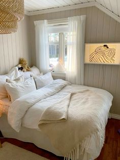 a white bed sitting in a bedroom next to a window