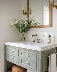 a bathroom with a sink, mirror and flowers in the vase on the counter top